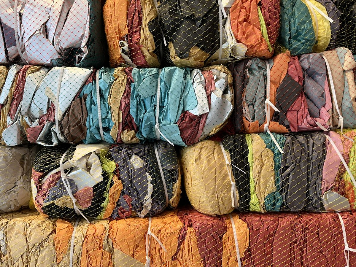 Compressed bales of colorful textile offcuts held with netting and straps