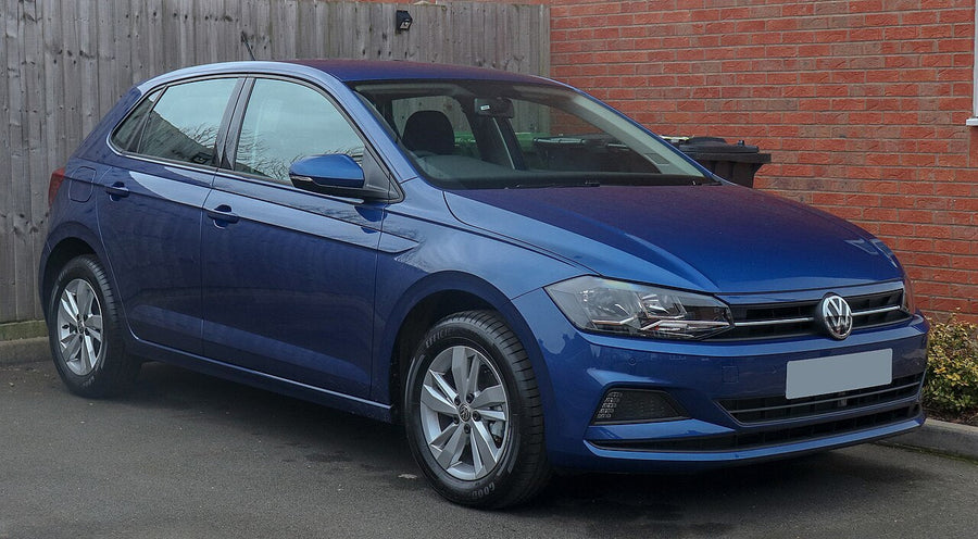 A blue Volkswagen Polo parked beside a brick wall.